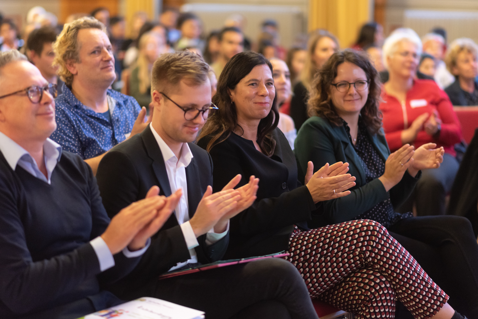 Viele Menschen sitzen im Plenum und applaudieren.