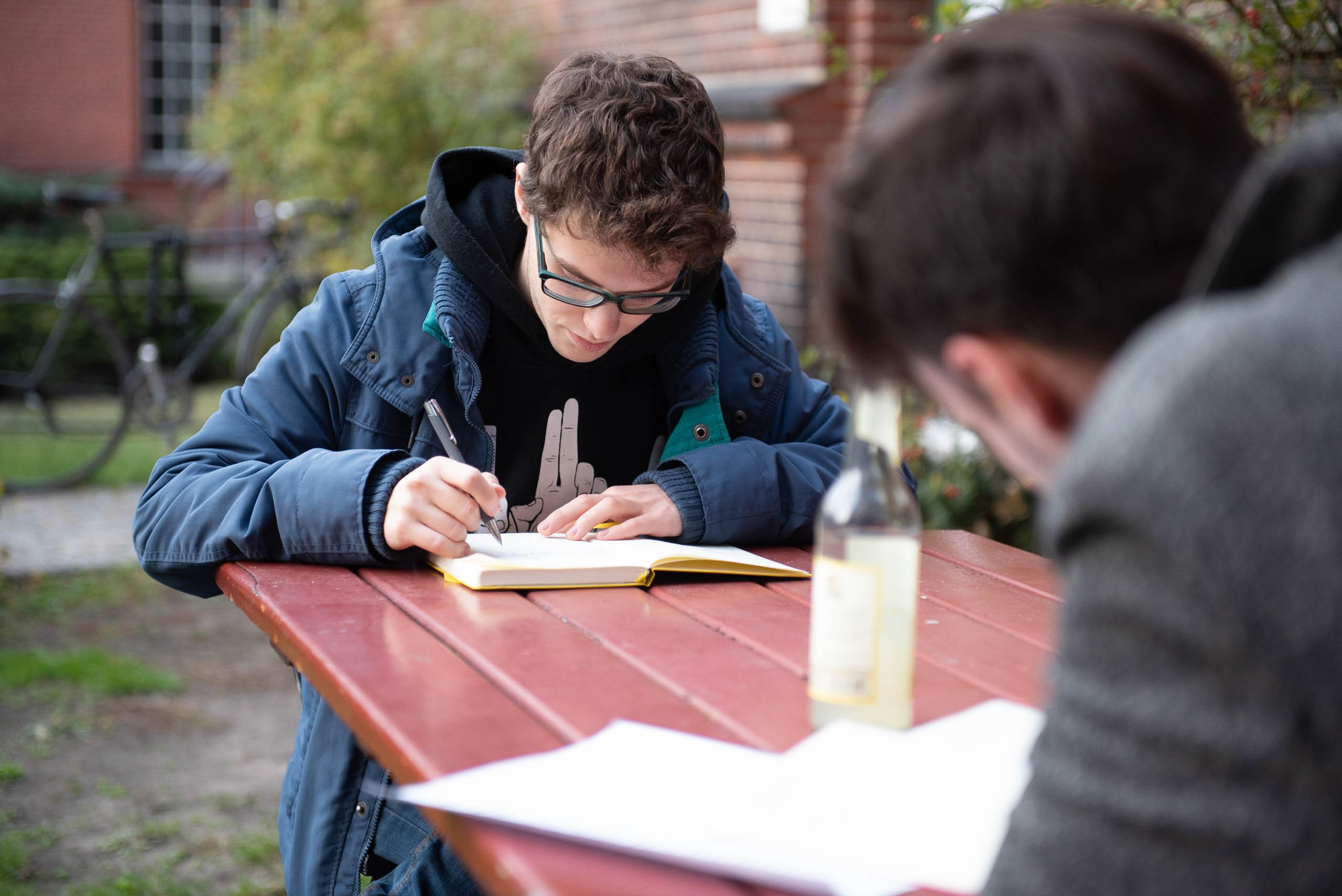 Auf dem Bild sieht man zwei Personen, die an einem Tisch sitzen und etwas aufschreiben. .© Servicestelle Jugendbeteiligung e.V., 2018