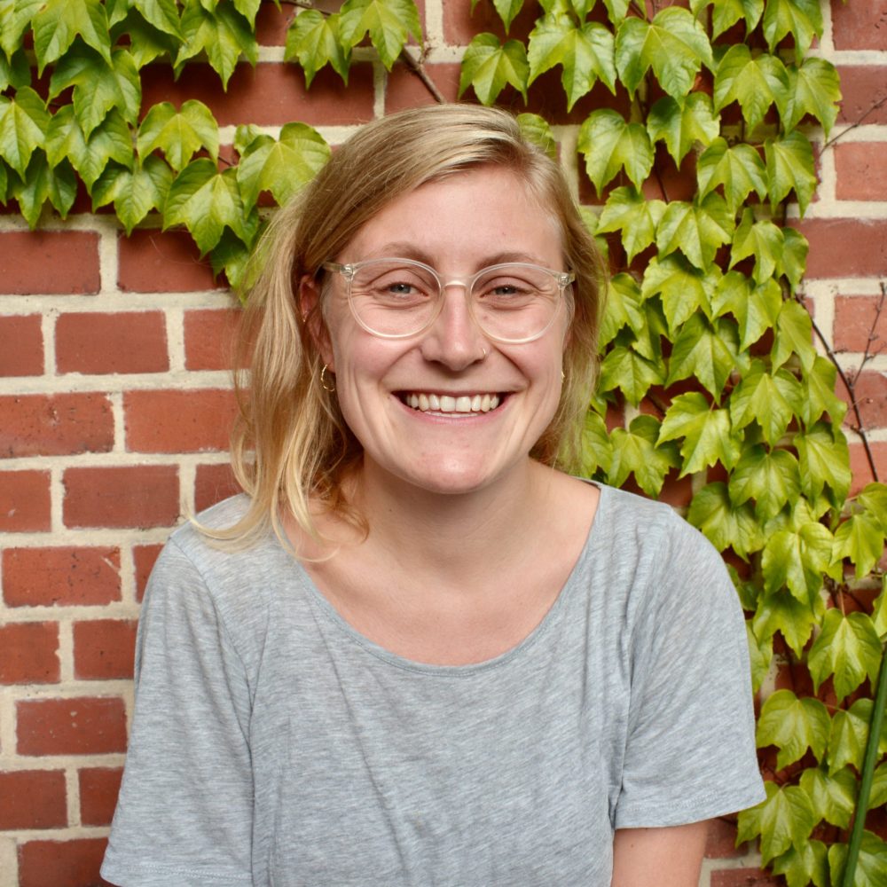Das Bild zeigt Anthea von der Servicestelle Jugendbeteiligung. Sie steht vor einer mit Efeu bewachsenen Backsteinwand und lacht in die Kamera. © Servicestelle Jugendbeteiligung e.V., 2020 Das Bild zeigt Anthea von der Servicestelle Jugendbeteiligung. Sie steht vor einer mit Efeu bewachsenen Backsteinwand und lacht in die Kamera. © Servicestelle Jugendbeteiligung e.V., 2020