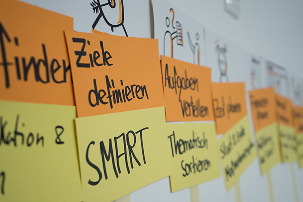 Auf dem Bild sind viele Moderationskarten zum Thema Projektmanagement an eine Wand gepinnt. Auf zwei deutlich erkennbaren Moderationskarten steht „Ziele definieren“ und „Smart“. © Servicestelle Jugendbeteiligung e.V., 2019