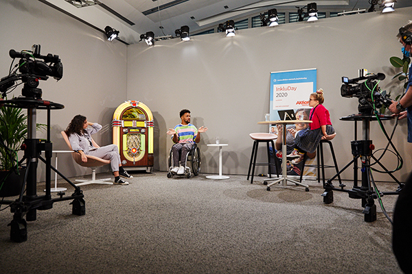 Das Bild zeigt die Moderatorinnen Ninia und Suri im Talk mit dem YouTuber Leeroy beim InkluDay 2020. Sie sitzen in einer Studiokulisse. © Anna Spindelndreier, 2020