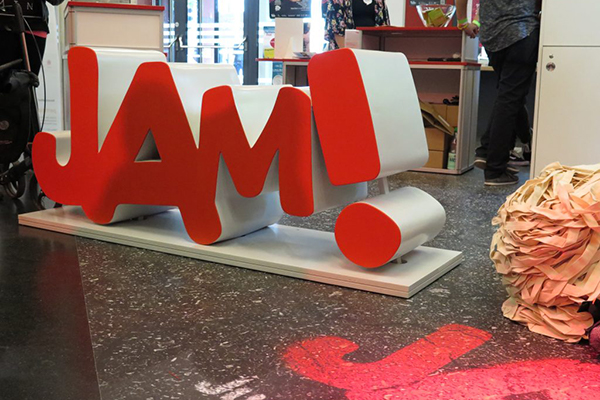 Der Schriftzug "JAM!" als großer roter Aufsteller steht auf dem Fußboden.