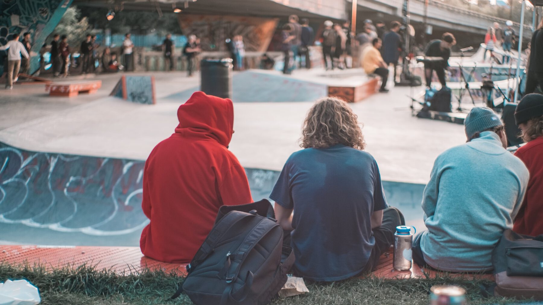 Jugendliche sitzen in einem Skatepark voller Menschen und chillen