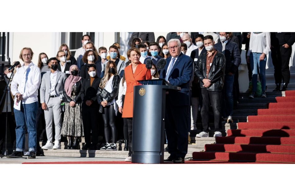 Auf dem Foto steht der Bundespräsident Frank- Walter Steinmeier vor einem Rednerpult und hält eine Rede. Hinter ihm steht eine Menschenmenge, die ihn anguckt und ihm zuhört. © dpa, 2021