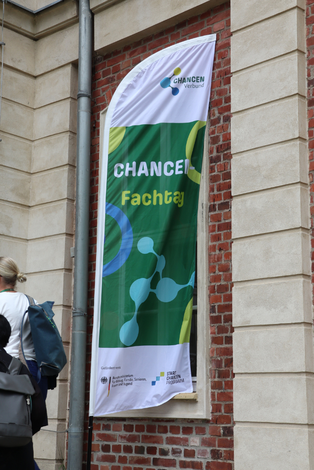 Fahnenständer mit grüner Flagge. Aufschrift mit "CHANCEN-Fachtag 2026".